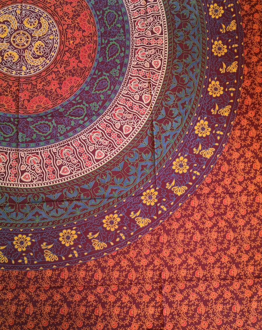 Magenta reds blues and turquoise circle with flowers indian tapestry, close up