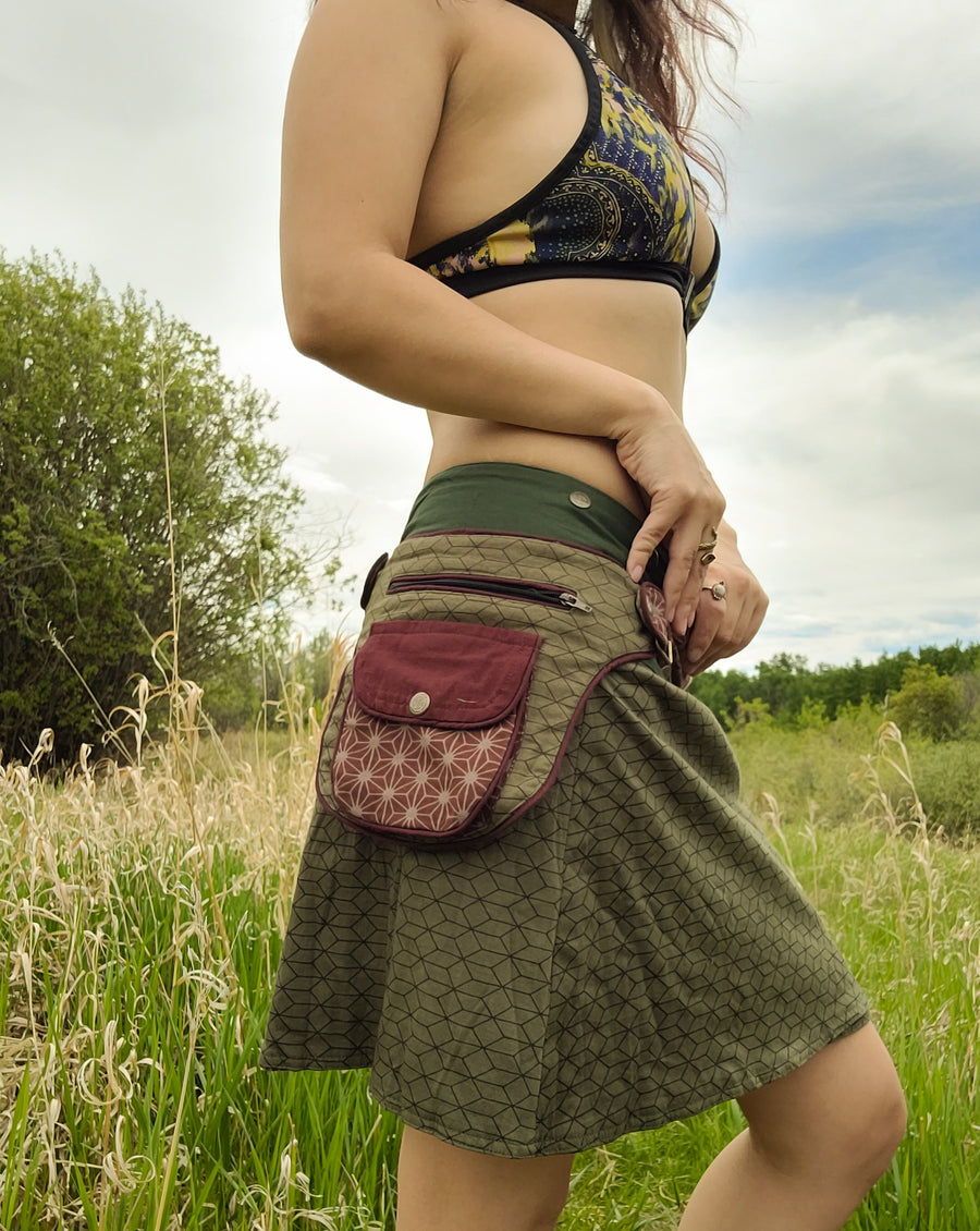 Lean body standing in field wearing the Arcane Coda skirt called the Flower of Life Snap Skirt.