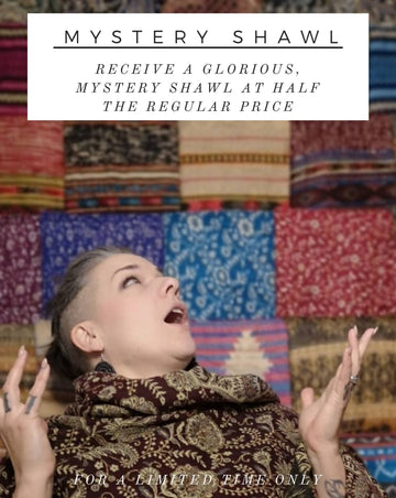 Woman is standing in front of a wall of colourful shawls with her hands up in awe, advertising a sale for Mystery Shawl at a discount.