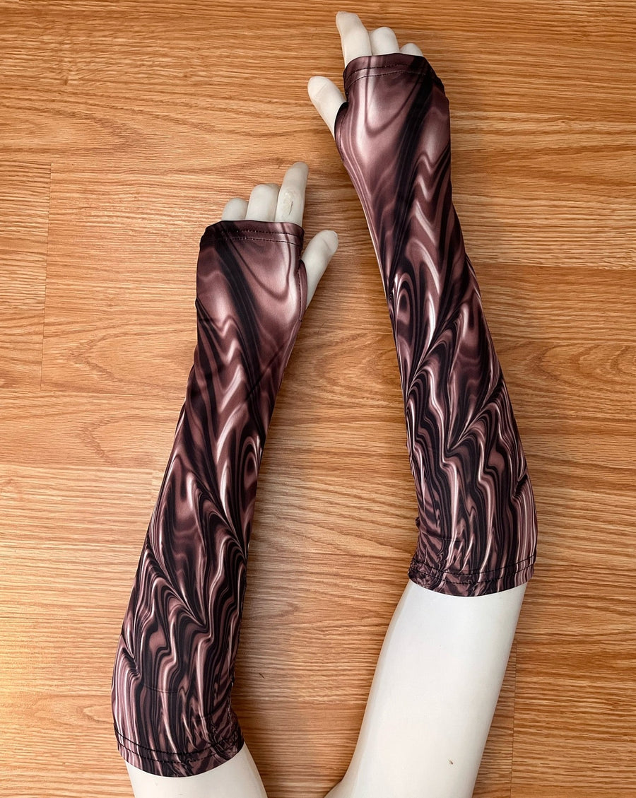 Mannequin hands lay on a laminate wood floor displaying colourful festival arms gauntlets.